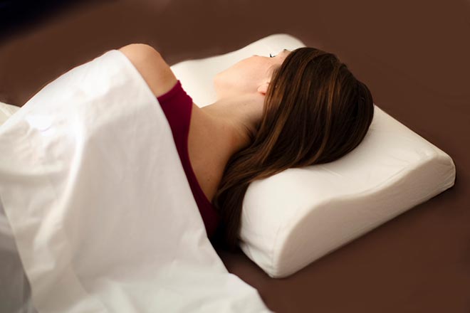 Девушка накрытая одеялом лежит боком на подушке с эффектом памяти