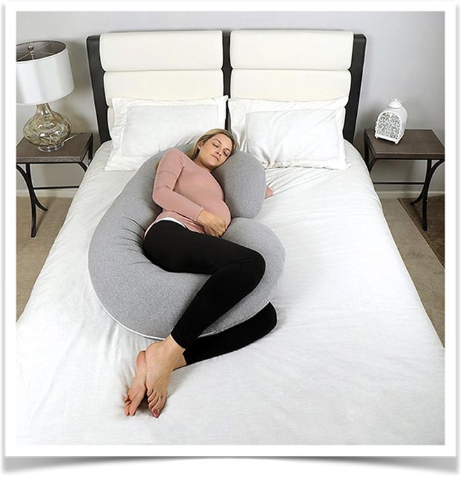 Девушка лежит с G подушкой для беременных на кровати
