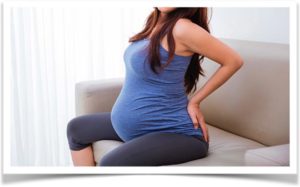Беременная женщина растягивает спину на диване